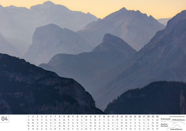 2025 Dolomiten Calendar, April, in English, Italian, French and German. Photograph of layers of blue mountains against a yellow sky.