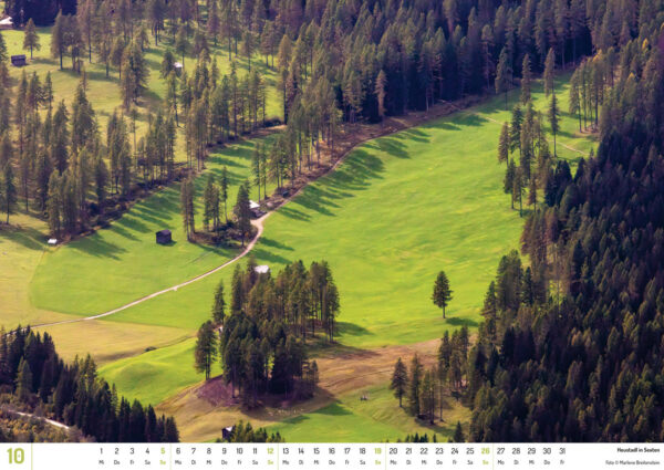 2025 Dolomiten Calendar, October. Photograph of farm sheds in Sexten's green valley.